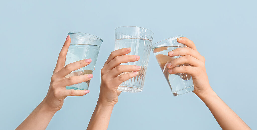 female,hands,with,glasses,of,water,on,light,blue,background
